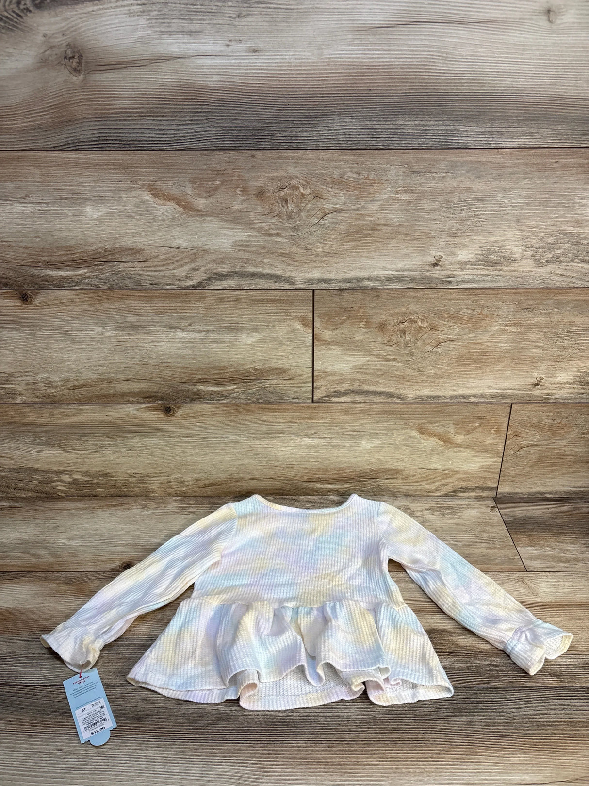 Long sleeve pastel ruffle toddler shirt with ribbed texture on wood background