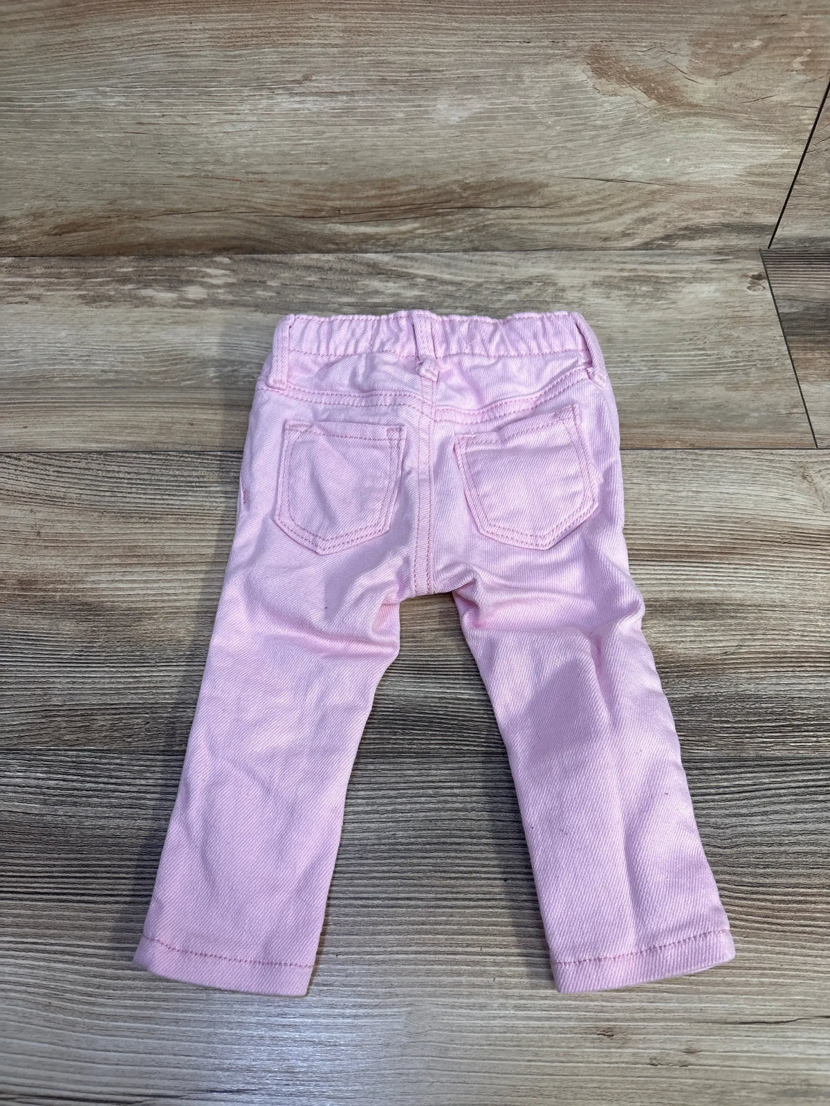 Back view of pink Old Navy toddler Rockstar jeggings size 12-18 months showing elastic waistband and back pockets on wood floor