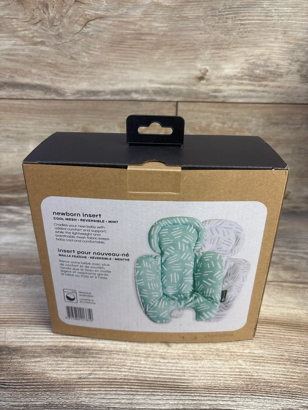 Front view of 4Moms Cool Mesh Newborn Insert in mint, showcasing reversible plush fabric in retail packaging against wood