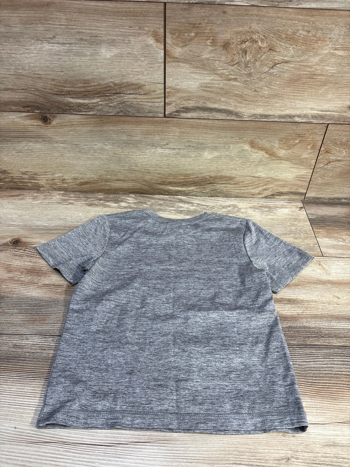 Back view of Adidas grey soccer shirt size 4T showing heathered fabric and short sleeves on light wood floor background