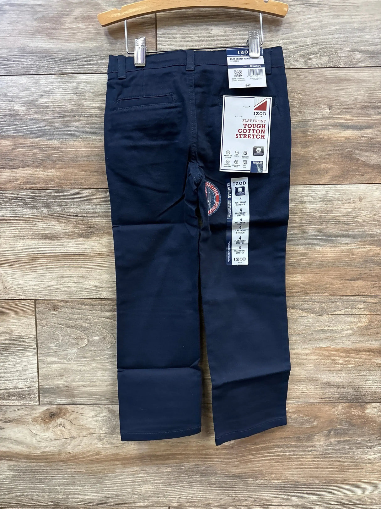 Front view of navy IZOD flat-front toddler pants size 4T showcasing attached brand tags and stretch cotton fabric with wood floor background