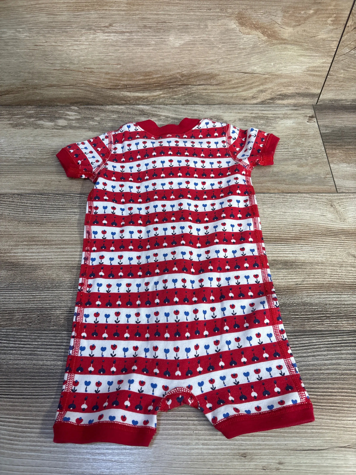 Front view of Hanna Andersson Floral Romper Sleeper showcasing patriotic red, white, and blue floral stripes on a wood floor
