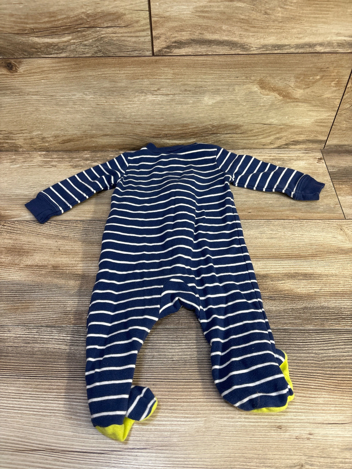 Flat lay of Carter's navy and white striped footed sleeper showcasing yellow feet on a wood plank background