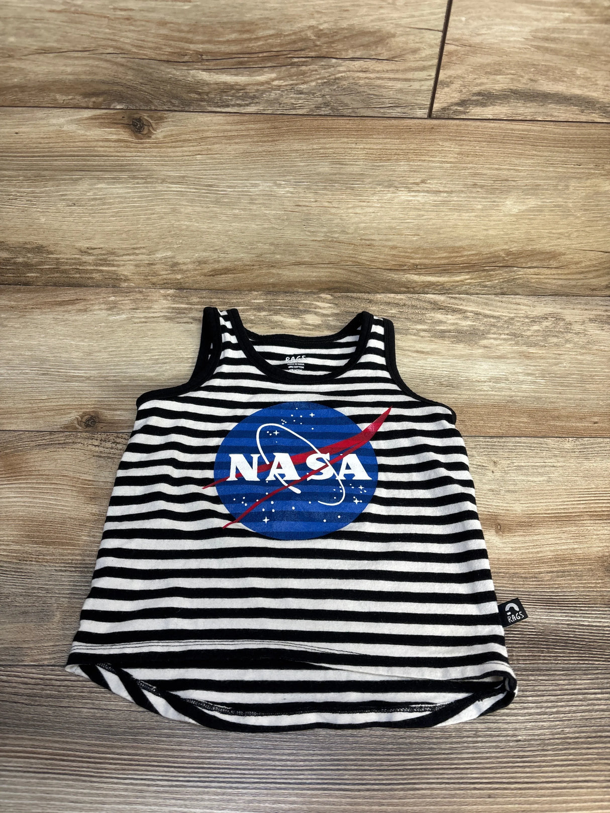 Kids black and white striped tank top with NASA logo, laid flat on wood floor.