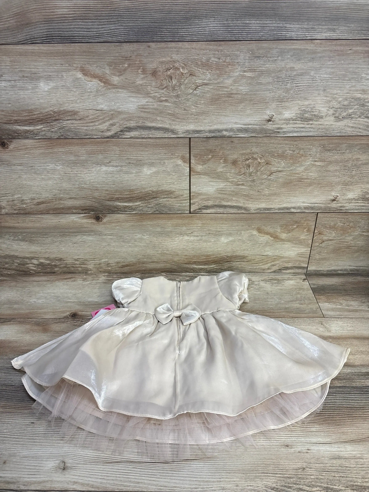 Top-down of Rare Editions gold dress and bloomers showing back bow, puff sleeves and layered tulle on wood background