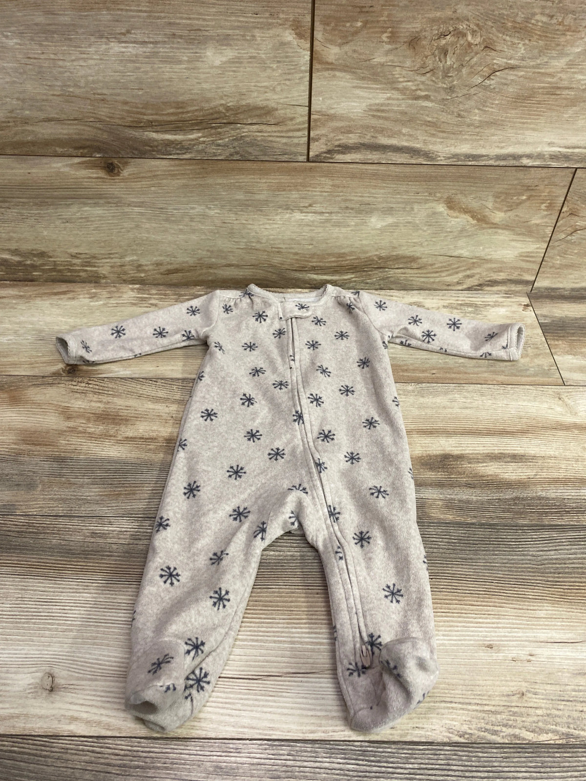 Front view of tan Just One You blanket sleeper size 6 months with snowflake pattern and front zipper on wood floor