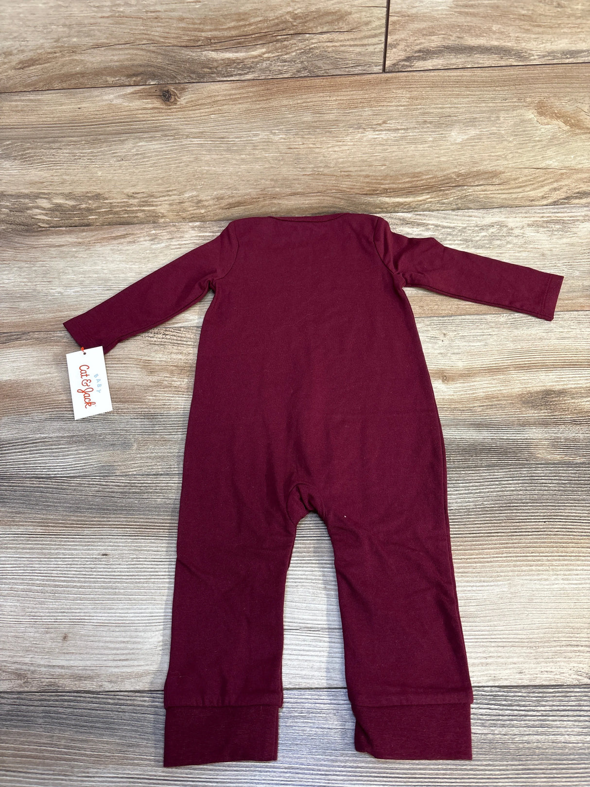 Maroon long-sleeve baby onesie laid flat on wooden floor with Cat & Jack tag