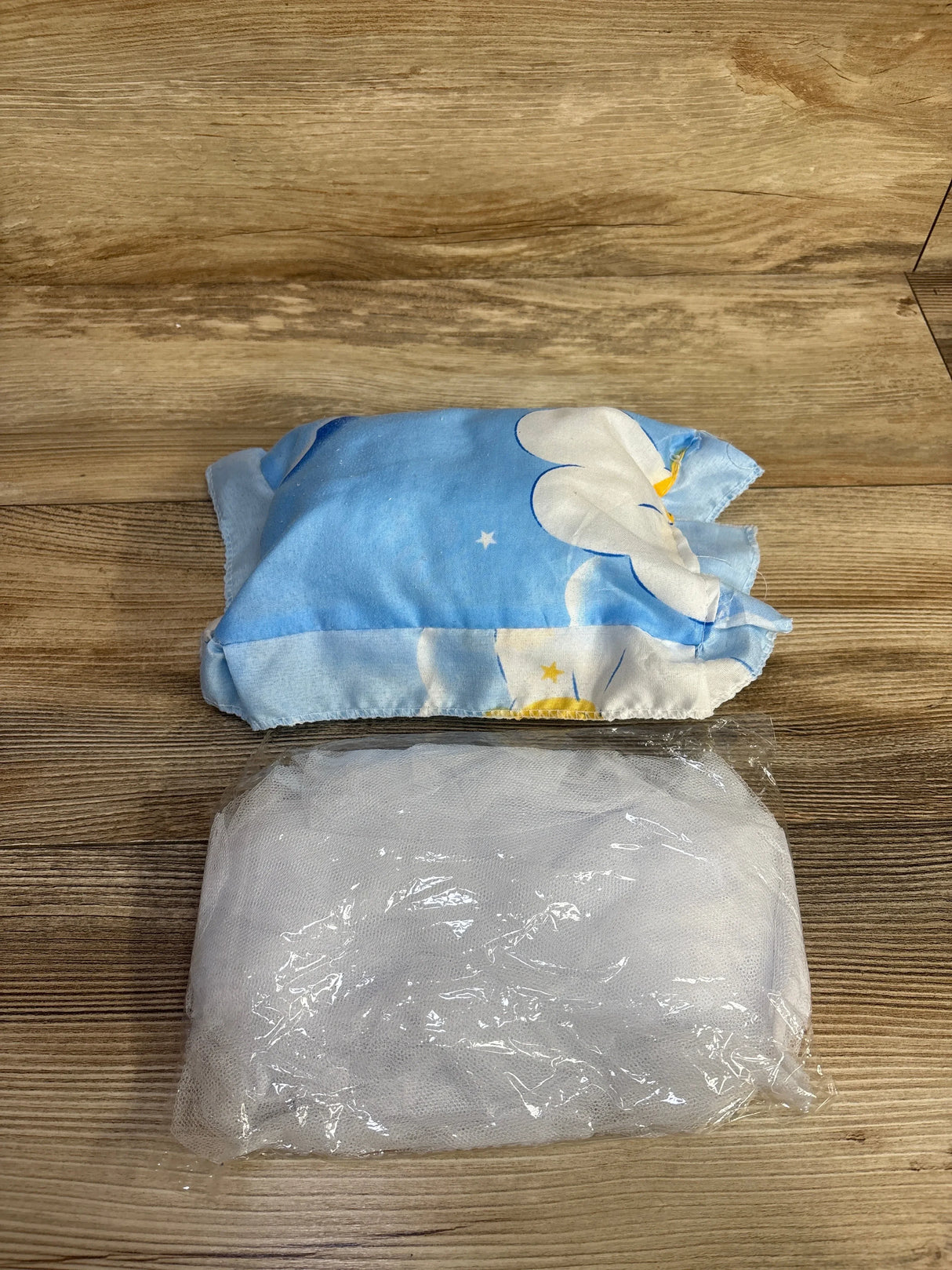 Blue cloth with white flowers and a folded white mesh cloth on a wooden surface