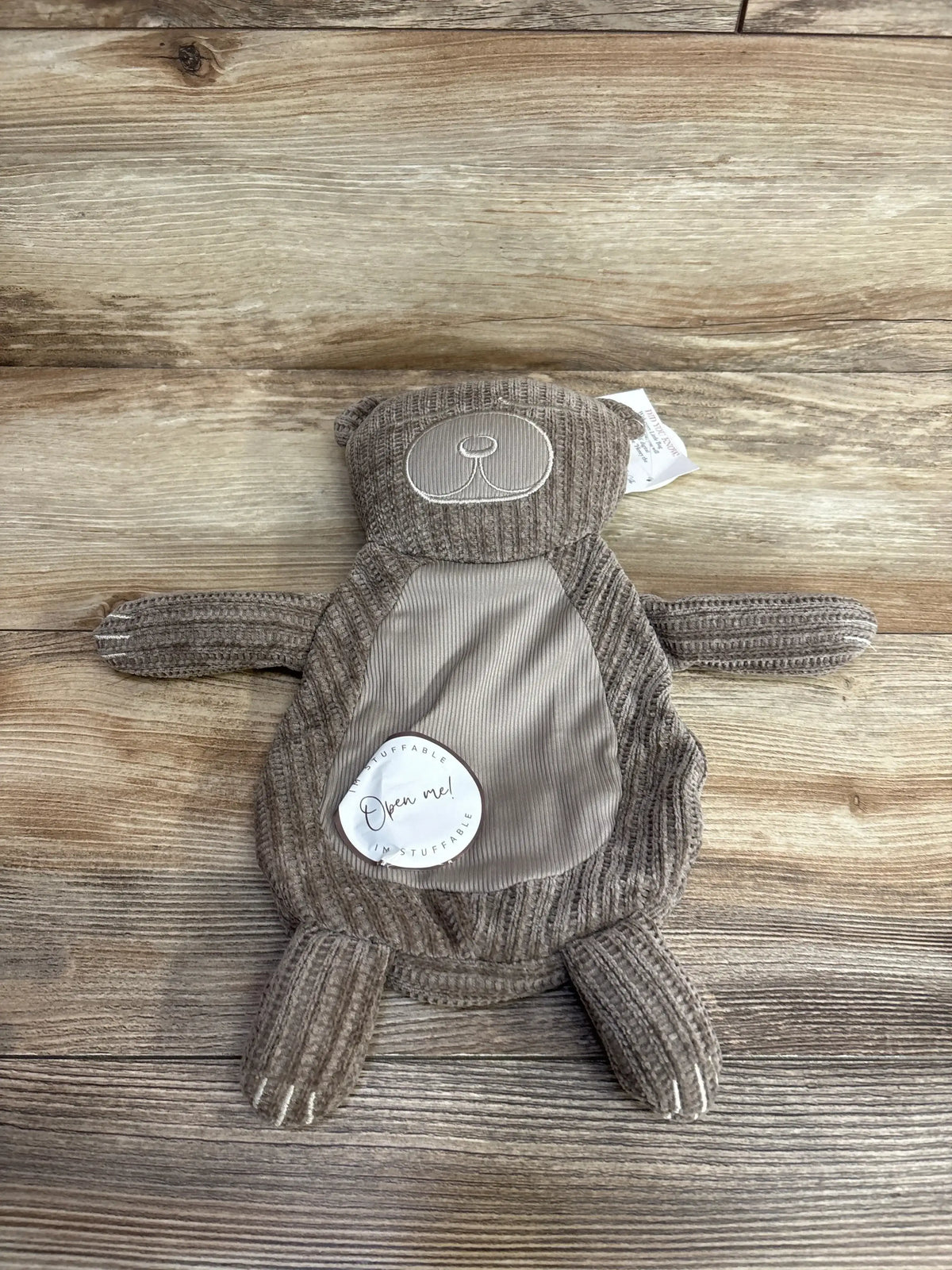Plush brown bear lovey toy with corduroy texture and stitched face on wood background
