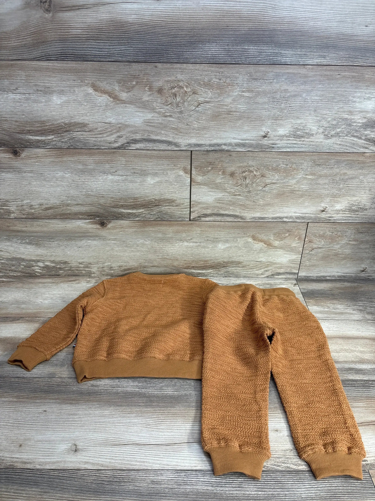 Flat lay of Sol Angeles oversized sweater and joggers, size 2T, showing textured knit and ribbed cuffs on wood background