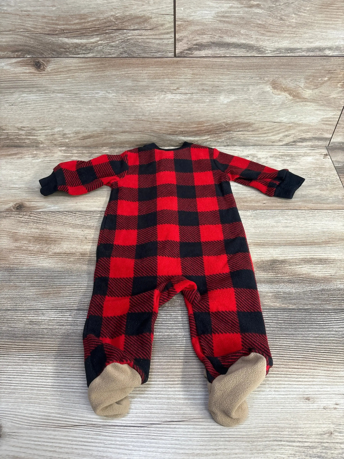 Red and black plaid baby sleeper with beige footies on wood background