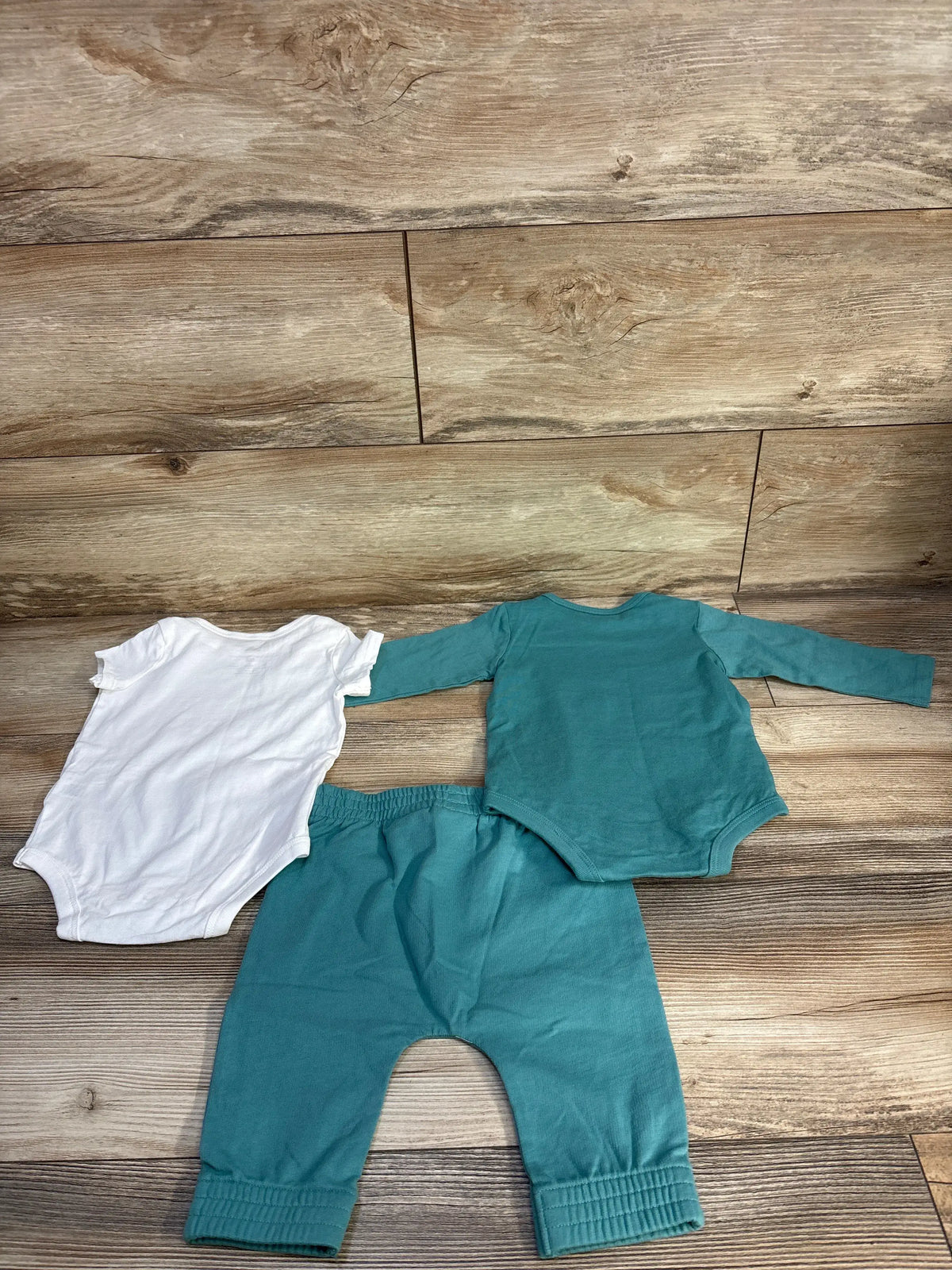 Top view of Adidas 3pc bodysuit set showing white short-sleeve and green long-sleeve bodysuits with green joggers