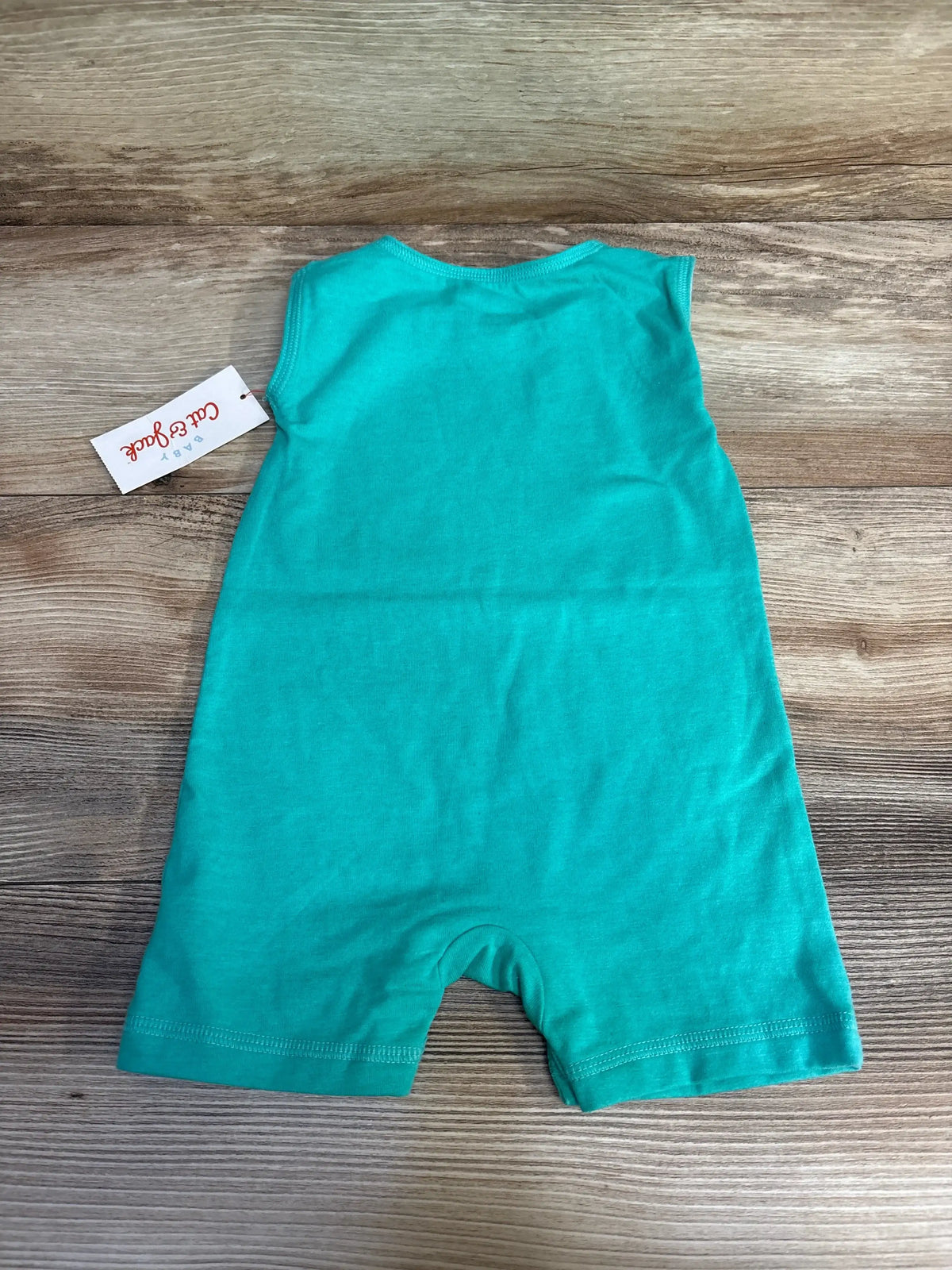 Back view of Cat & Jack green baby romper showcasing short legs and attached hang tag with wood plank background