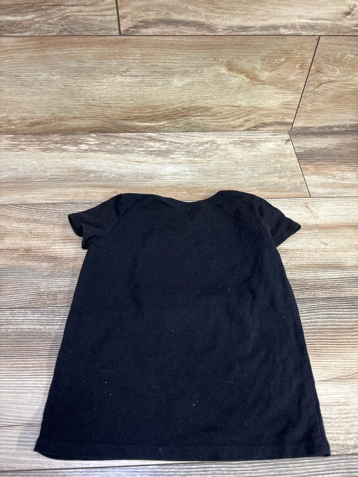 Back view of Children’s Place ABC’s shirt in black, size 5T, showing short sleeves on a wood-look floor