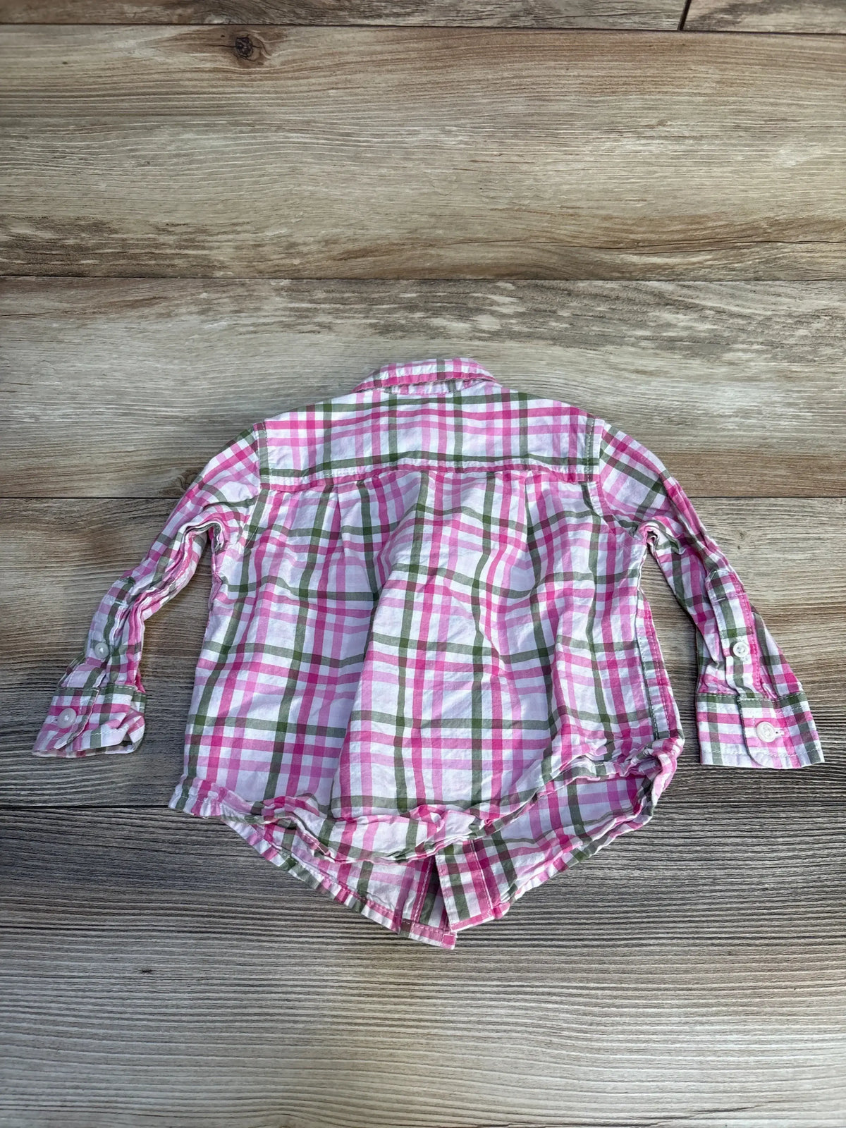 Pink and green plaid long sleeve toddler shirt on wood background