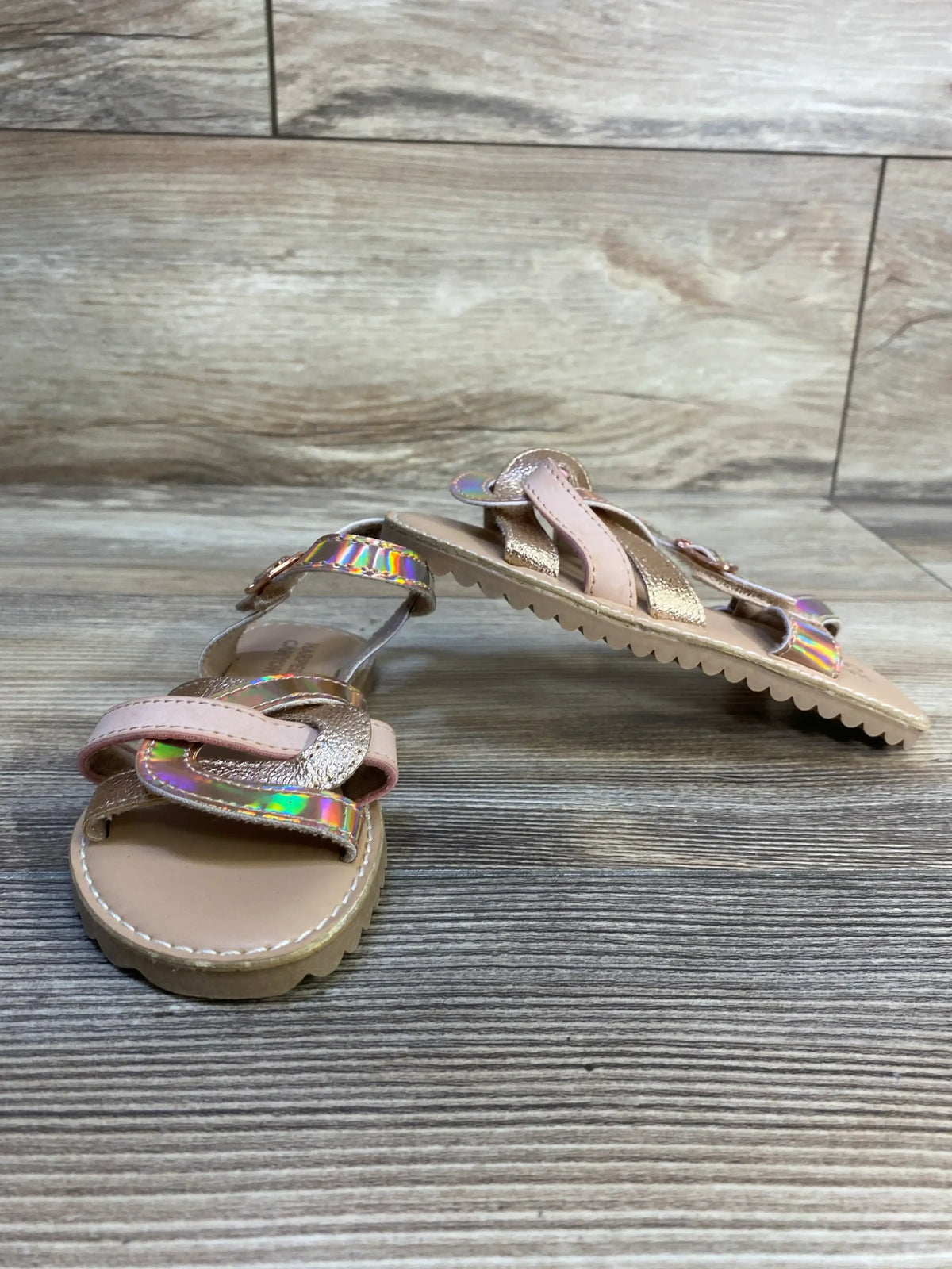 Three-quarter view of Harper Canyon Finley strappy sandals size 10C in tan with iridescent pink and gold straps on wood floor