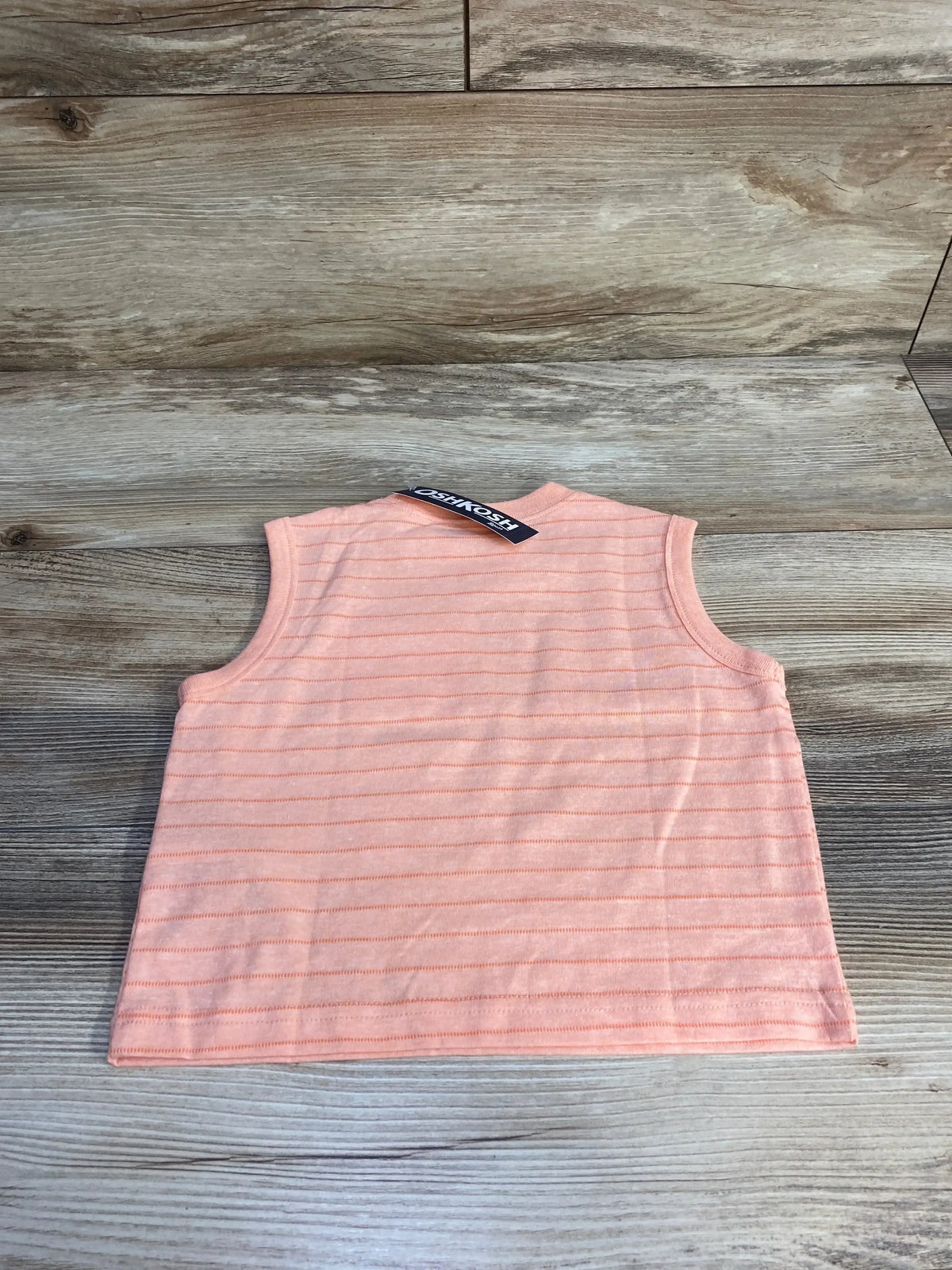 Back view of OshKosh pink striped sleeveless tank top for 12 months showing thin horizontal stripes on wood plank background