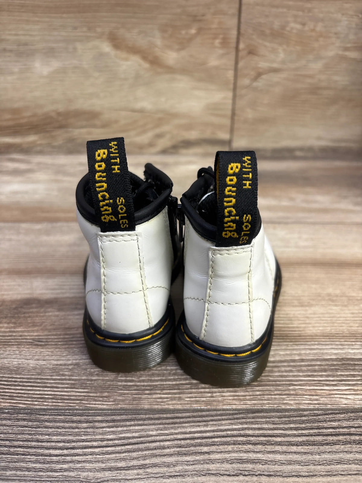 Rear view of white Dr. Martens 1460 leather boots, size 4C, showcasing black pull tabs, yellow stitching, and black soles