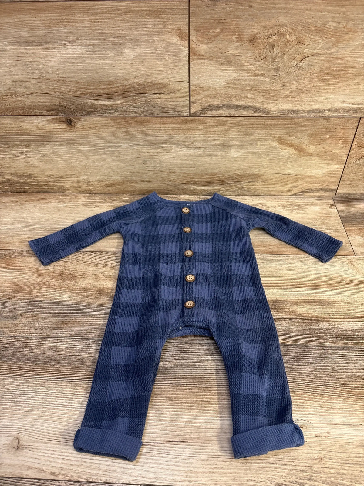 Front flat lay of Mud Pie waffle knit blue checkered coverall with wood buttons, rolled cuffs on wood surface size 6-9 months