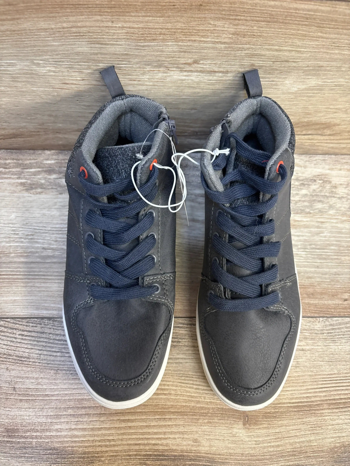 Top view of Art Class Geoff high-top kids sneakers in grey showcasing navy laces and white rubber soles on wood floor