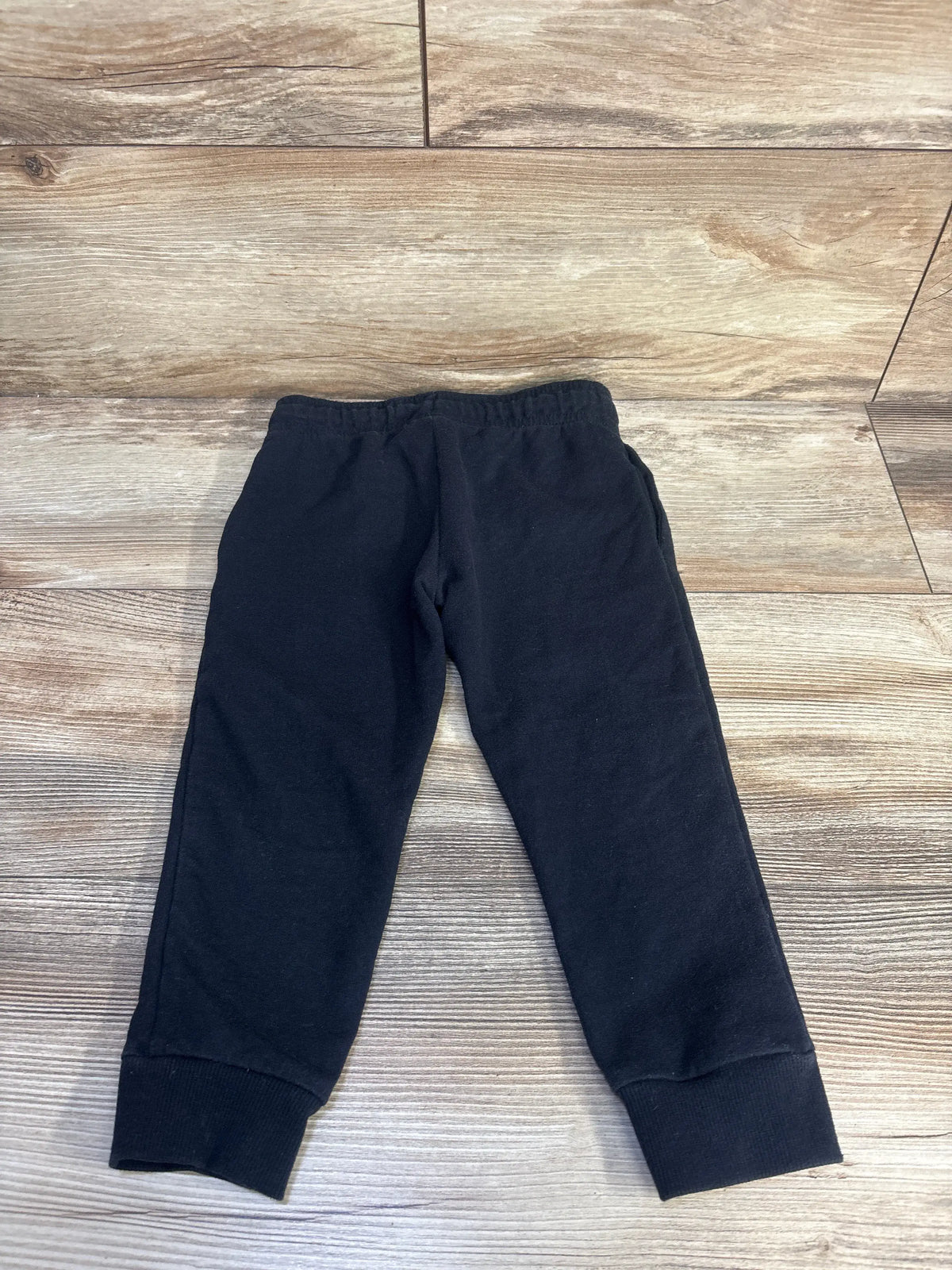 Front view of Carter’s black pull-on drawstring joggers in size 3T showcasing elastic waistband and ribbed cuffs on a wood floor