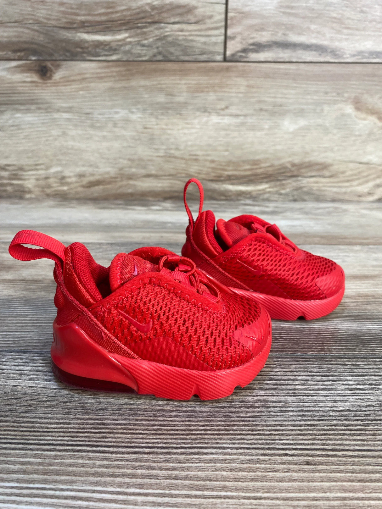 Red toddler athletic sneakers with mesh upper on wooden background