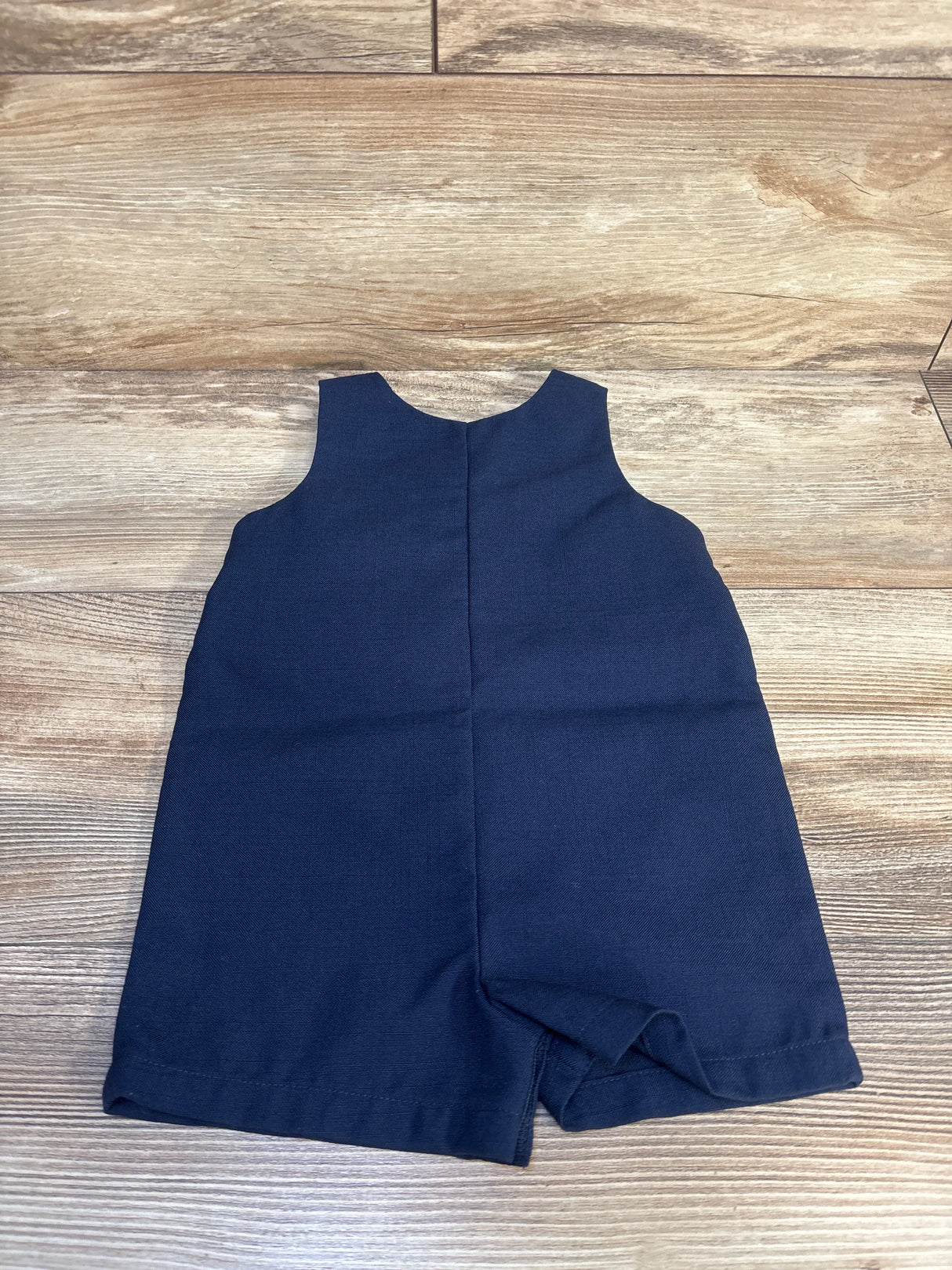 Navy blue sleeveless toddler romper laid flat on wooden surface