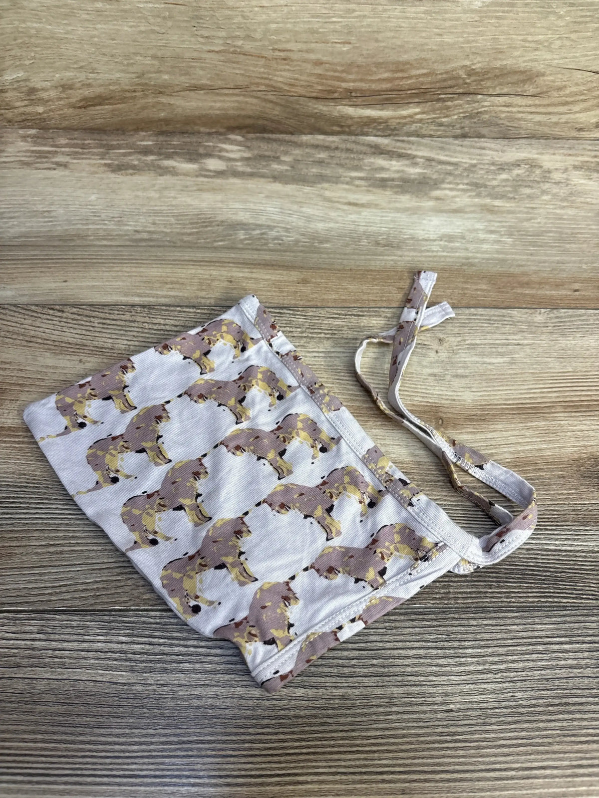 Top-down view of Kate Quinn Water Unicorn Bonnet showcasing watercolor unicorn print and tie straps with light wood background