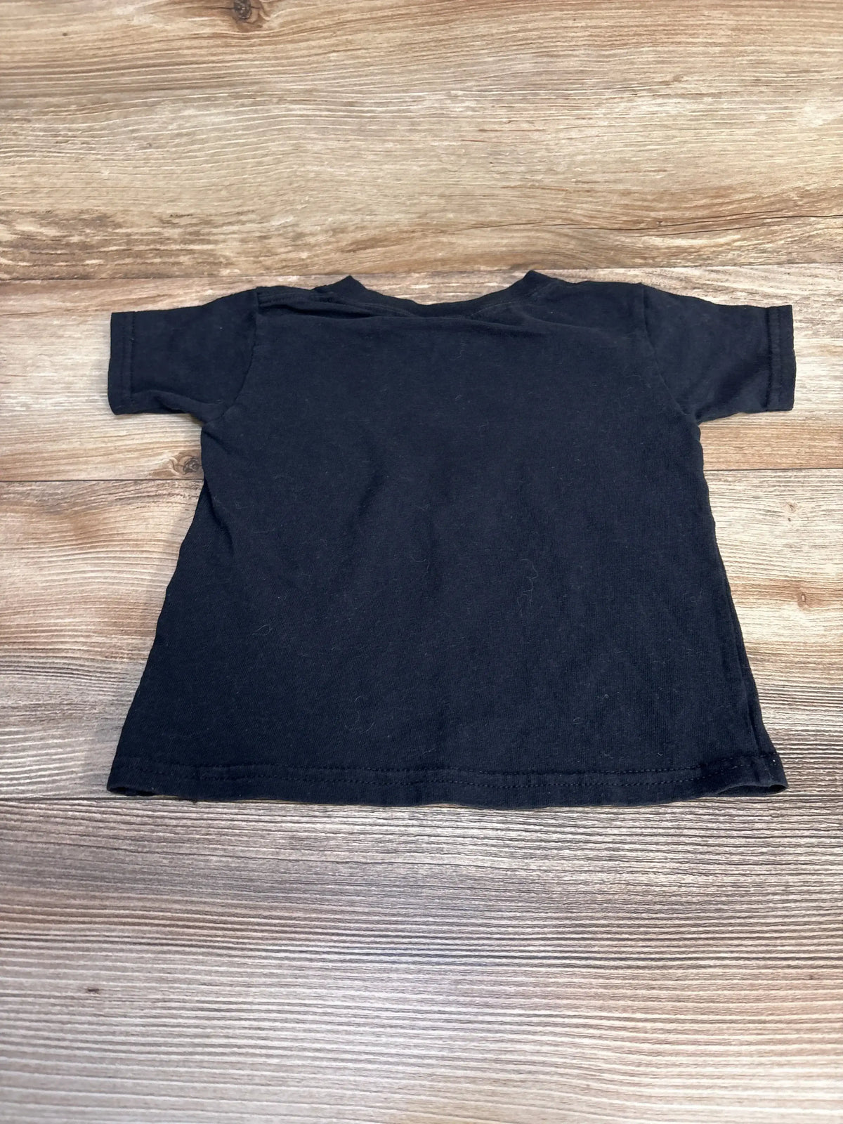 Black short sleeve toddler t-shirt laid flat on wood surface