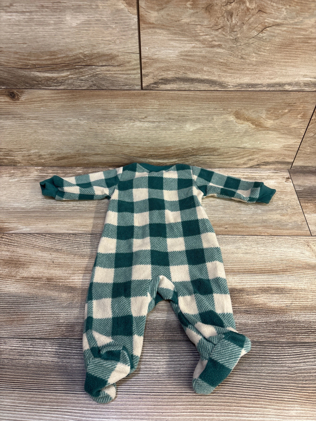 Flat lay of newborn blanket sleeper with green and cream buffalo check, long sleeves and covered feet on wood background
