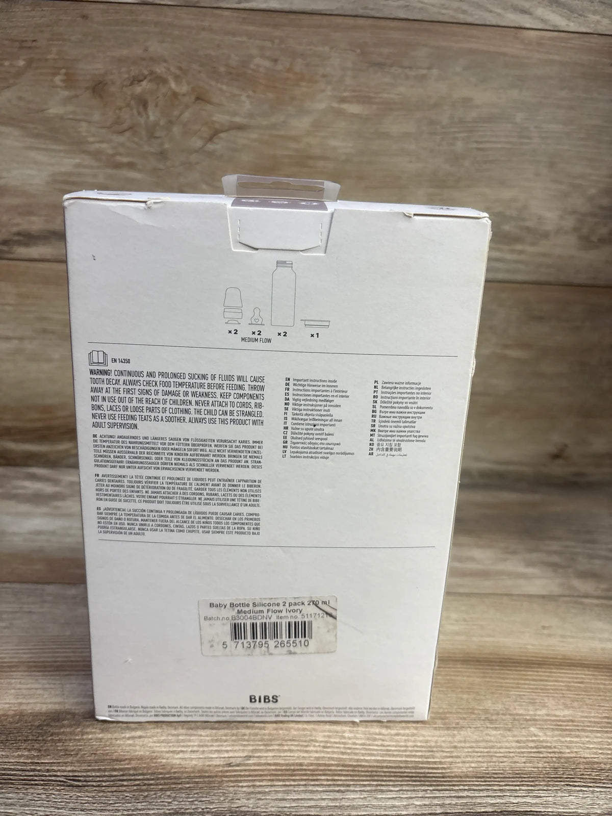 Back view of NEW BIBS 2-pack medium-flow baby bottles showing package contents and safety instructions on a wooden surface