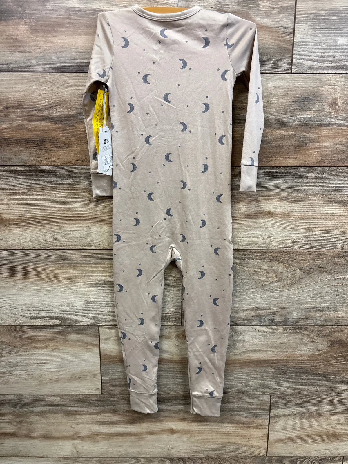 Back view of Cloud Island tan moon-print one-piece sleeper size 4T showcasing long sleeves, cuffed ankles on wood background