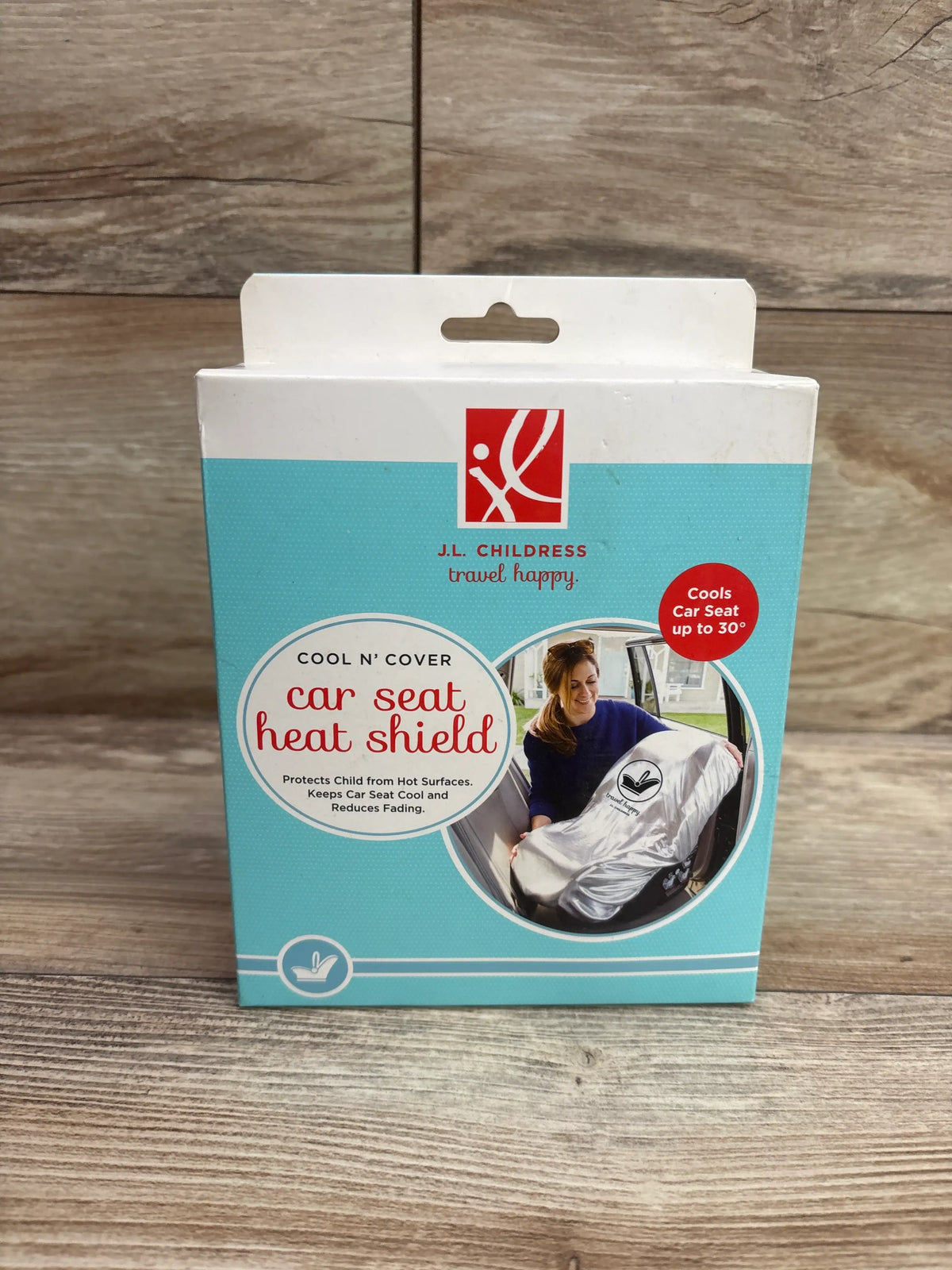 Front view of J.L. Childress Cool N Cover car seat heat shield package showcasing cooling up to 30 degrees on a wood-grain surface