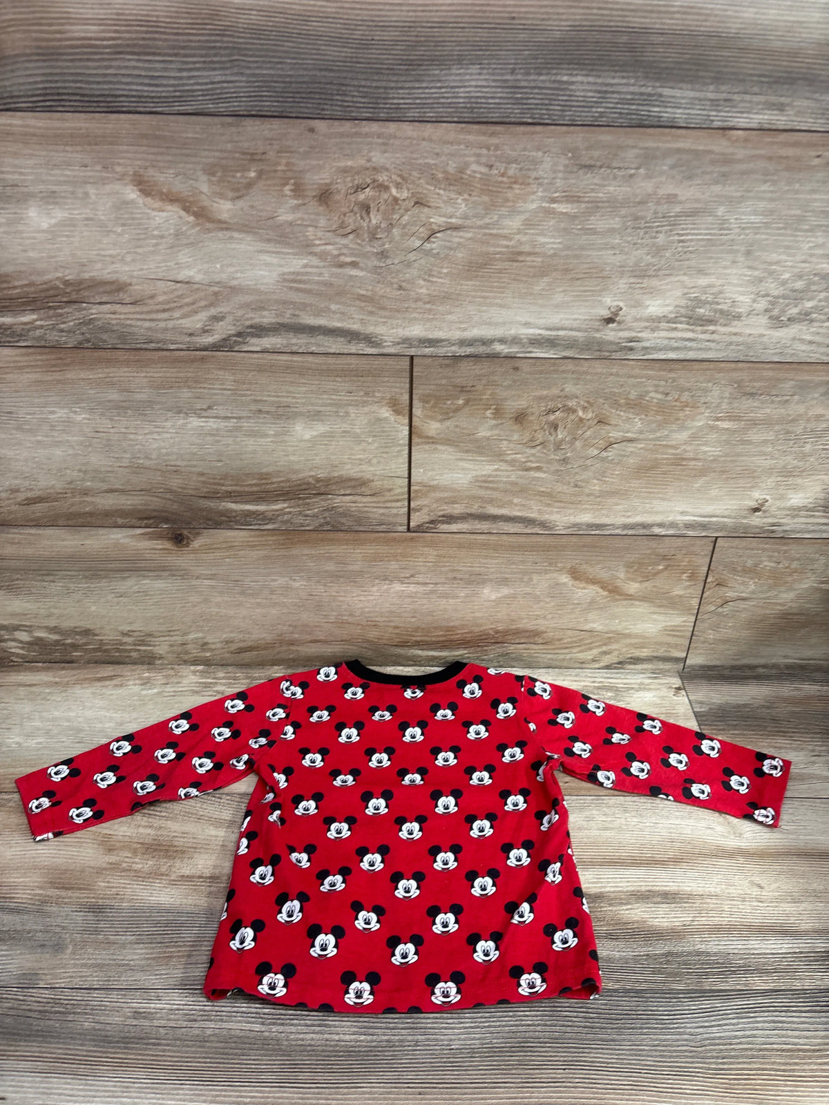 Red long sleeve toddler shirt with all-over Mickey Mouse print on a wood background