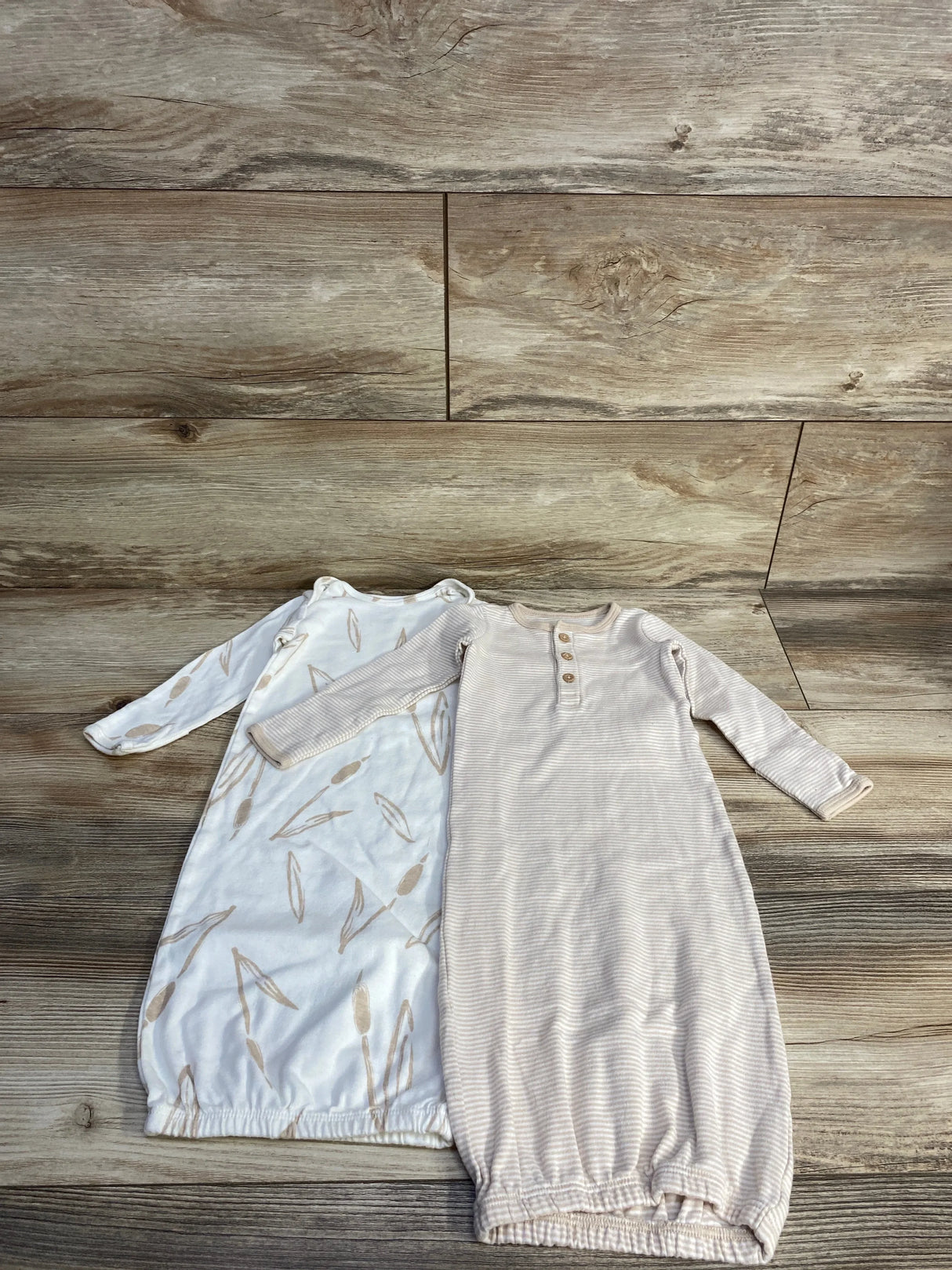 Flat lay of two Carter's sleeper gowns: tan striped gown with button placket and elastic hem, white gown with tan leaf print