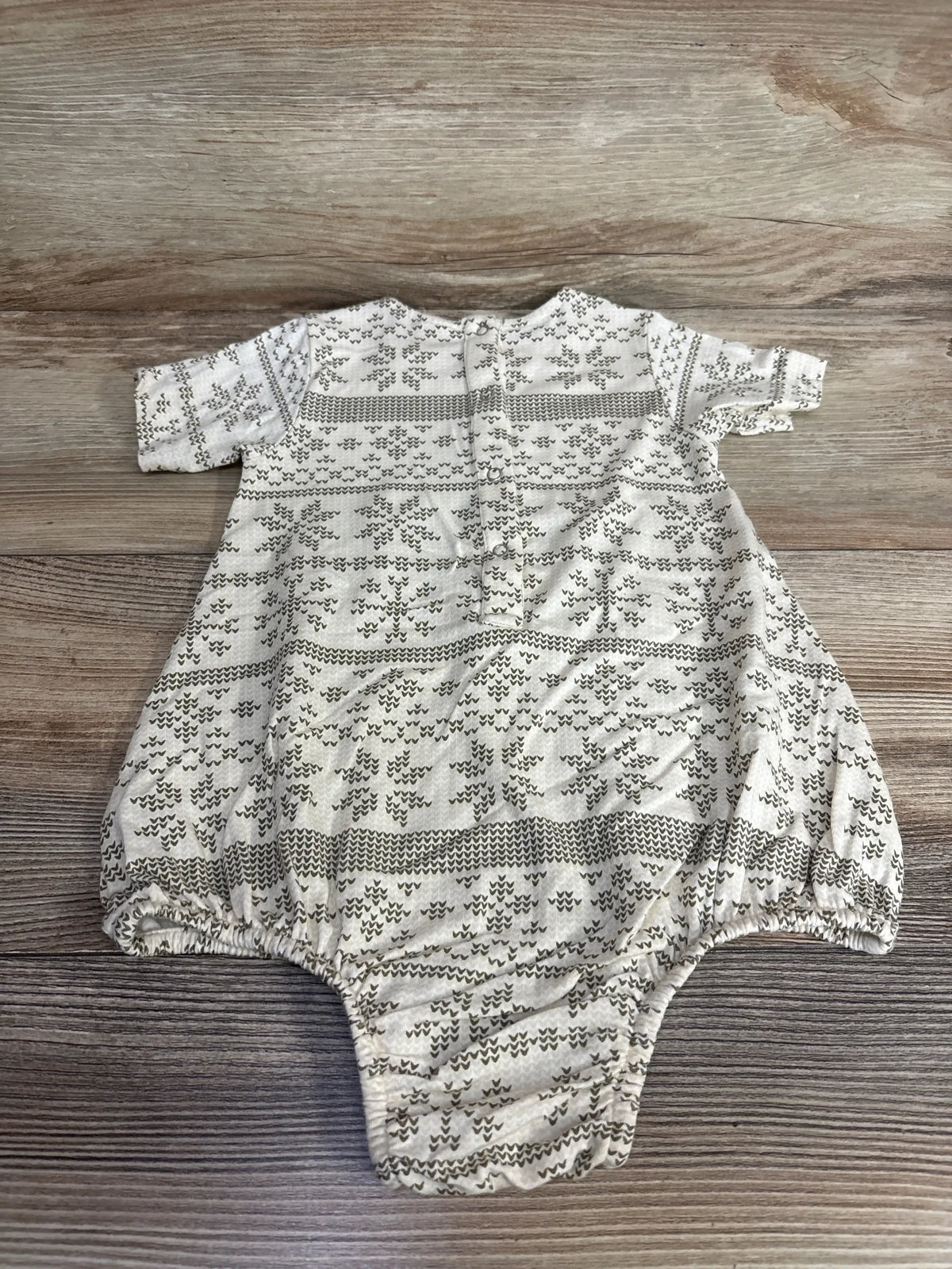Front view of Kate Quinn kangaroo pocket bubble romper showcasing patterned organic cotton fabric and elastic leg openings on wood