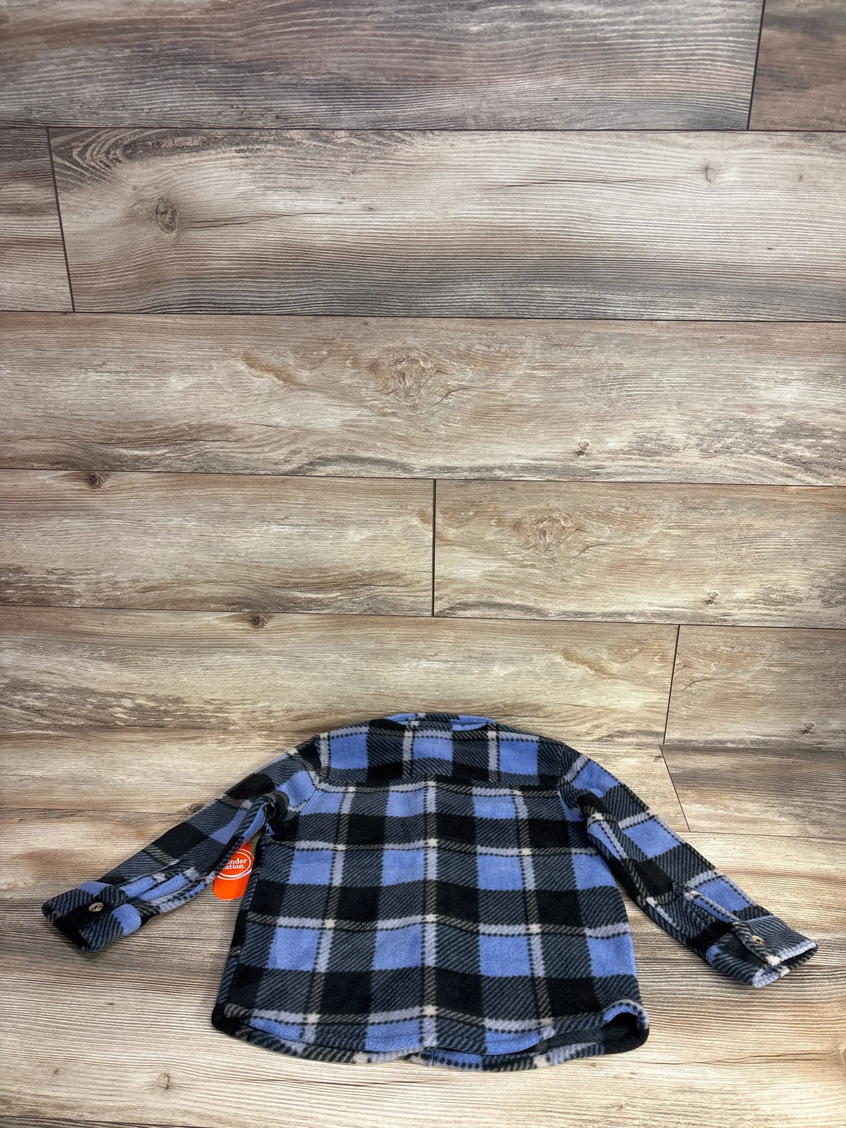 Blue and black plaid long sleeve fleece kids shirt on wooden surface