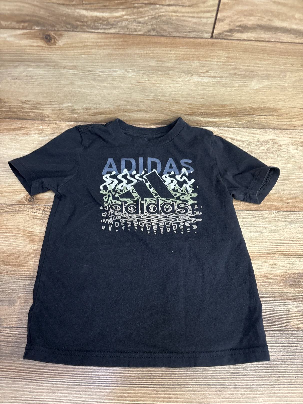 Black adidas kids t-shirt with graphic logo on wood background