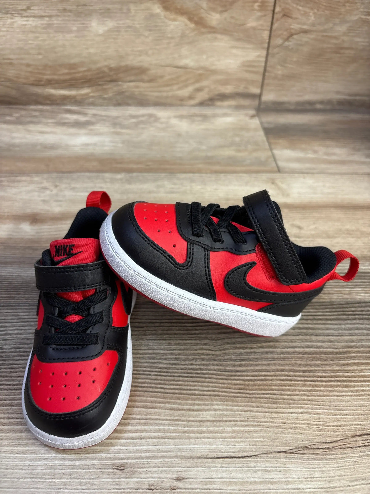 Angled view of Nike Court Borough Recraft TD shoes in University Red and Black showing black laces, straps, and white soles