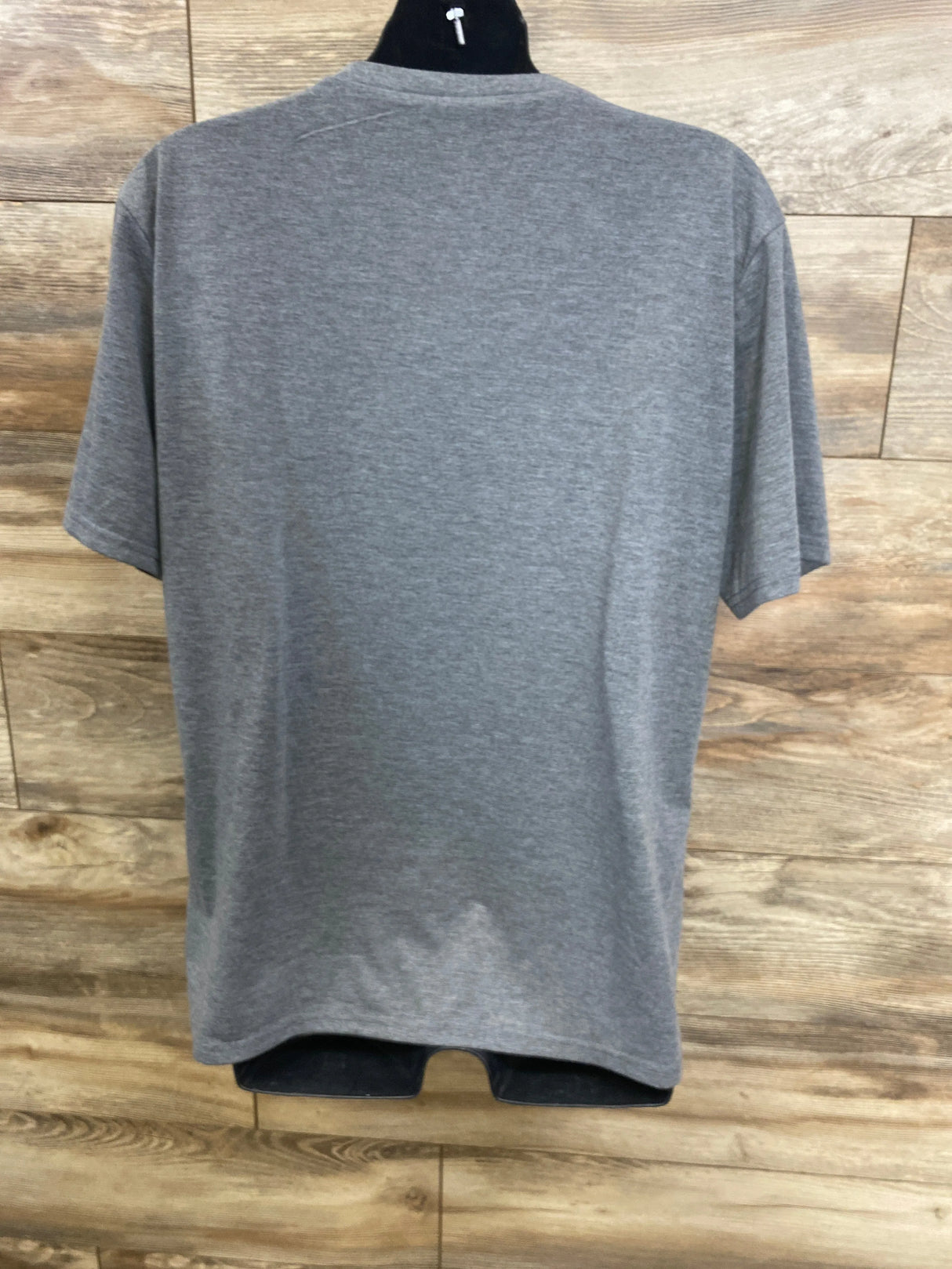 Back view of a plain gray short sleeve kids t-shirt on hanger against wood background