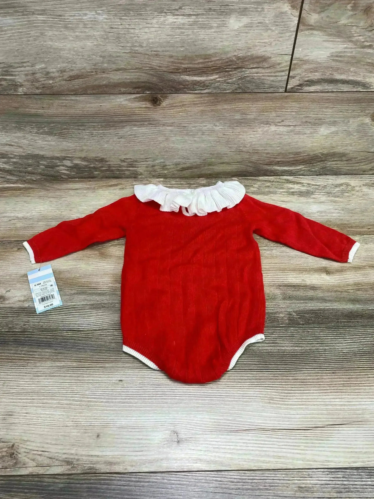 Front view of red Cat and Jack ruffle collar romper, size 6 to 9 months, with white ruffle collar and long sleeves on wood