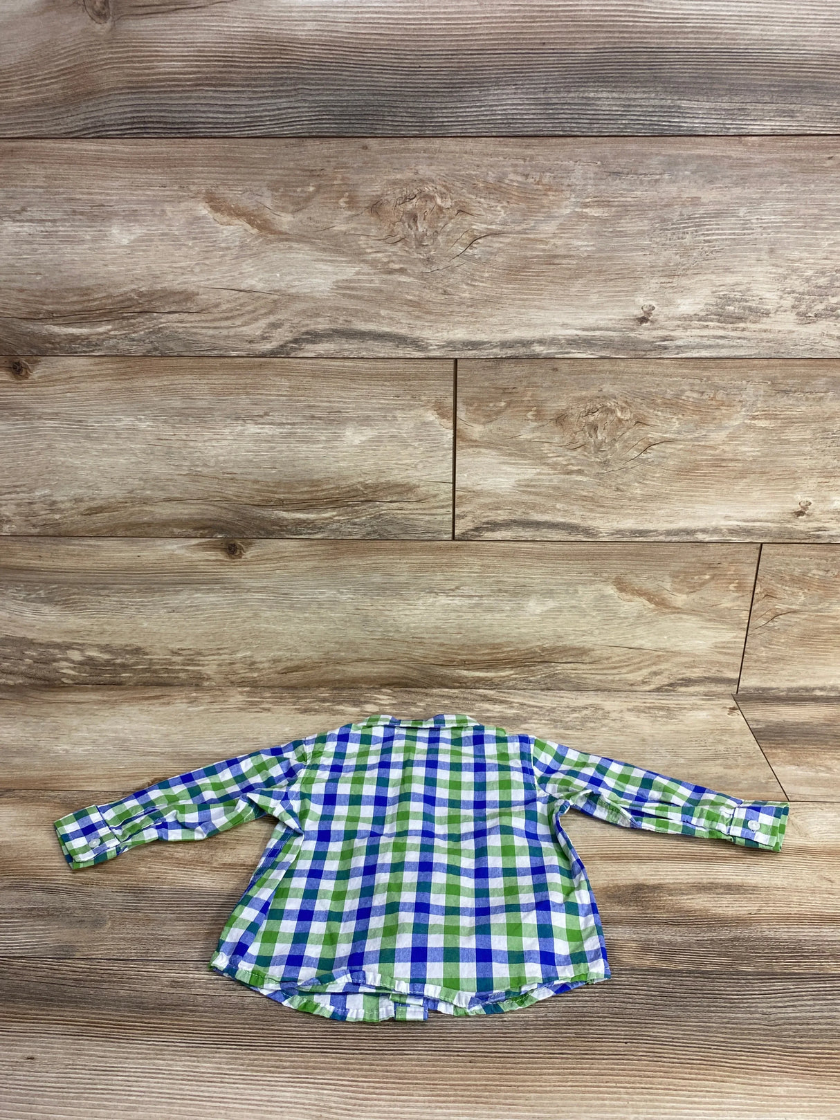 Green and blue plaid long sleeve toddler shirt on wood background