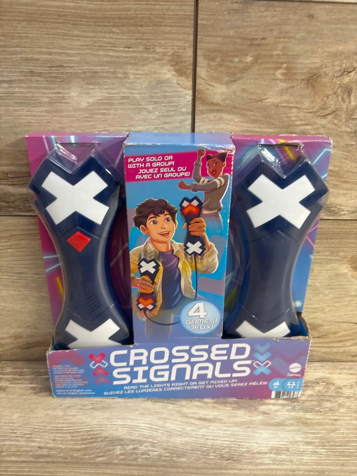Crossed Signals electronic game for kids, two handheld controllers in retail packaging, on wood background