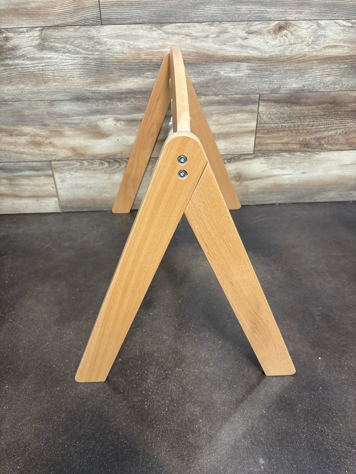Side view of Pottery Barn Kids Wooden Activity Gym showcasing its wooden arch frame against a wood plank background