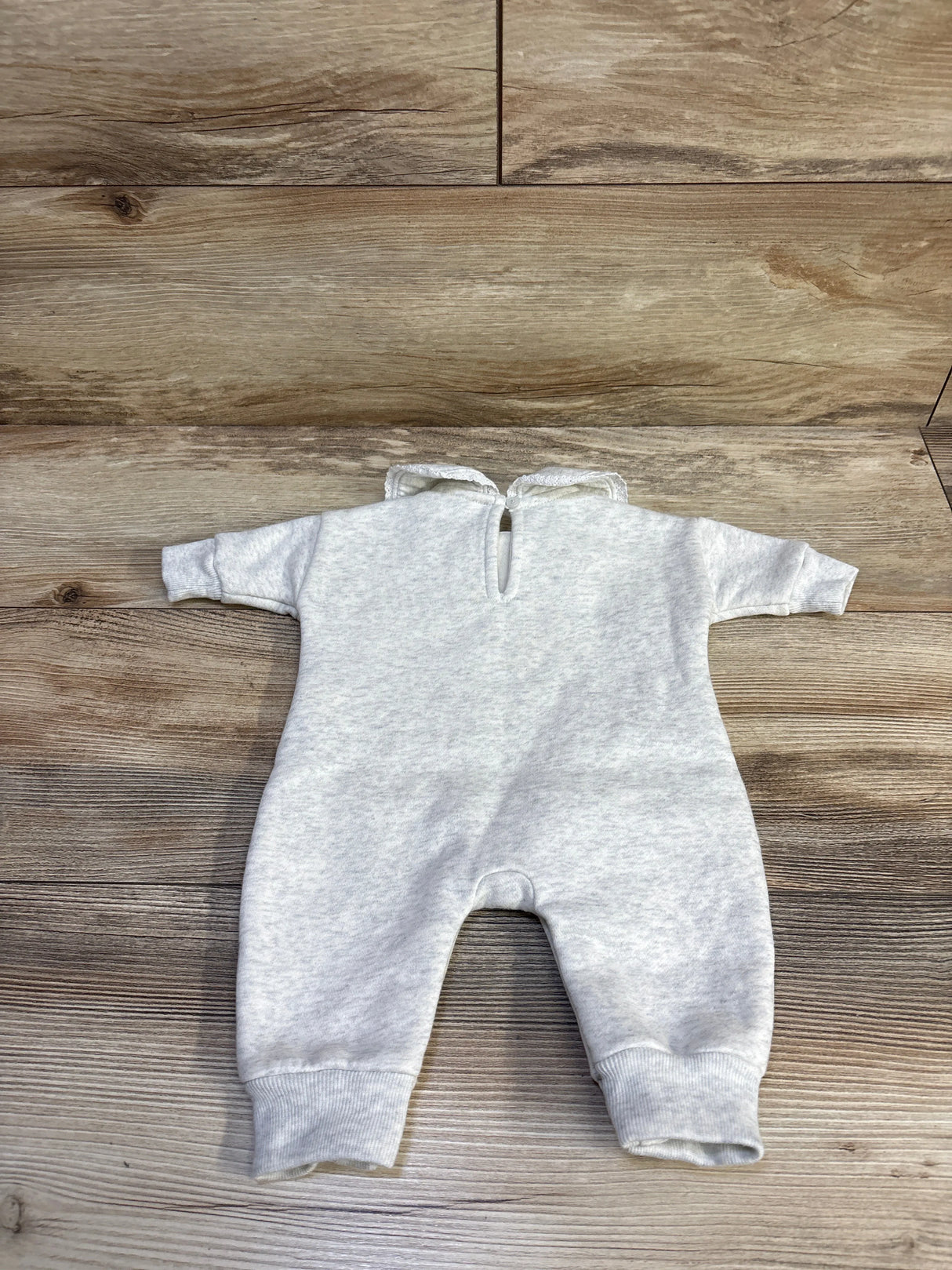 Back flat lay of Baby Gap grey collared fleece newborn jumpsuit with lace-trim collar and keyhole back on wood background