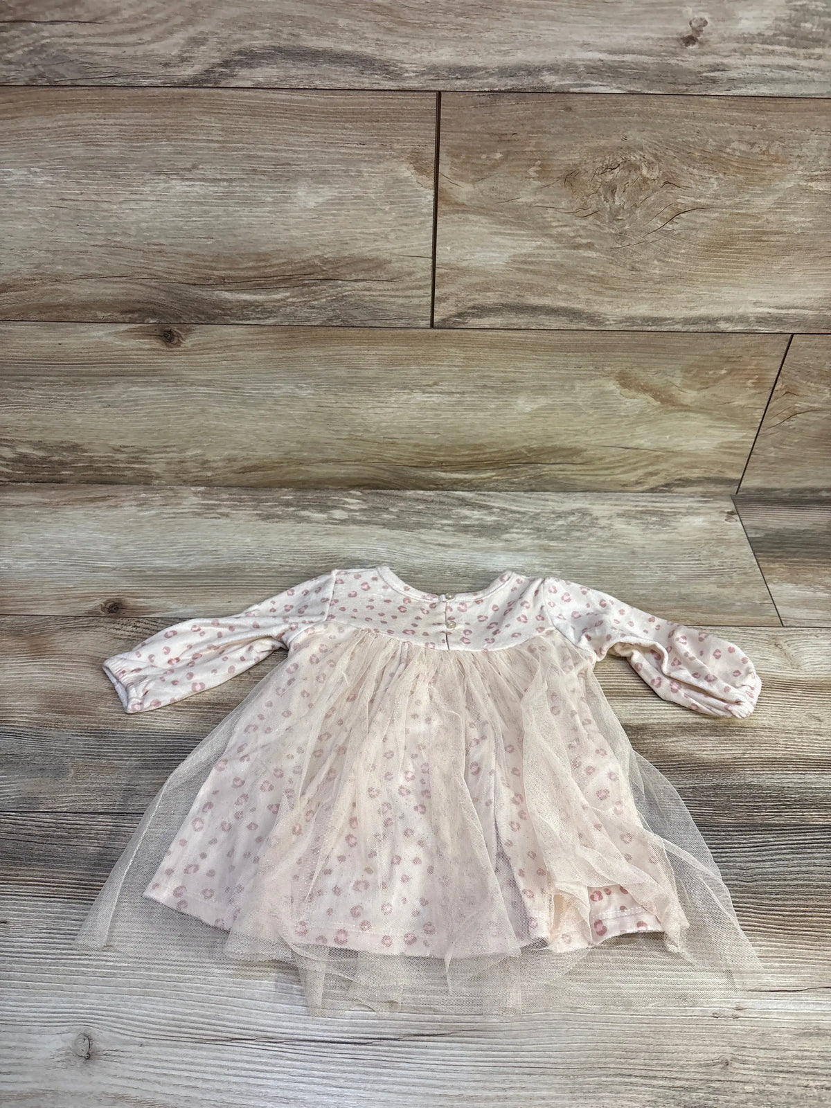 Top-down view of Chick Pea leopard-print velour baby dress (3-6m) showcasing tulle overlay and long sleeves on wood plank background
