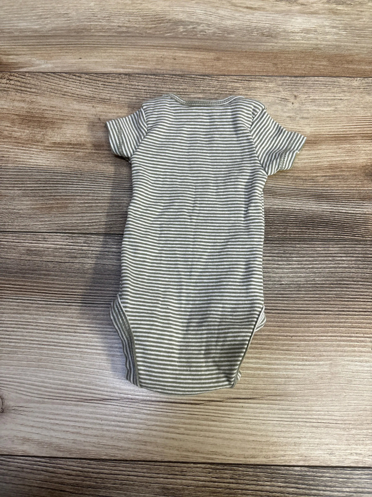 Flat lay back view of Carter’s preemie bodysuit in green and white stripes showing short sleeves and envelope neckline on wood background