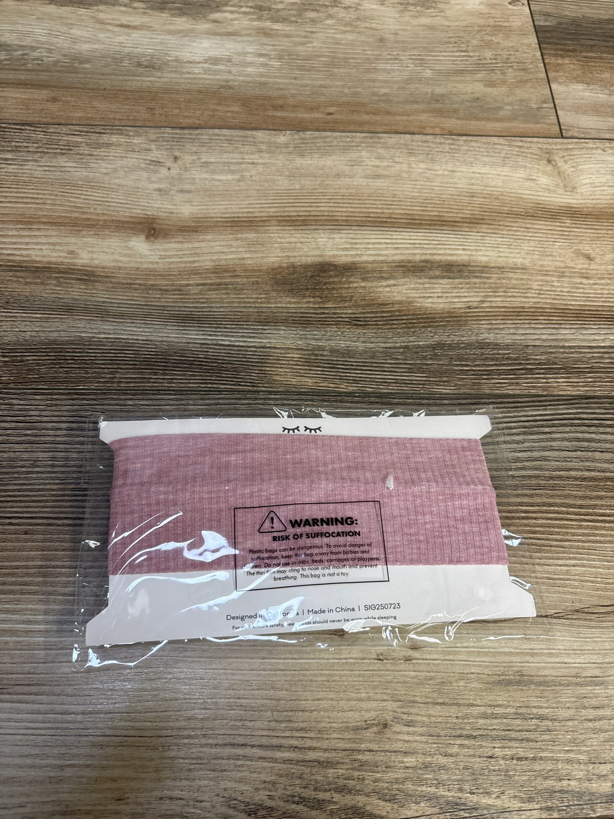 Top-down view of Little Sleepies Ribbed Luxe Bow Headband in mauve showing ribbed texture and bow on wood floor