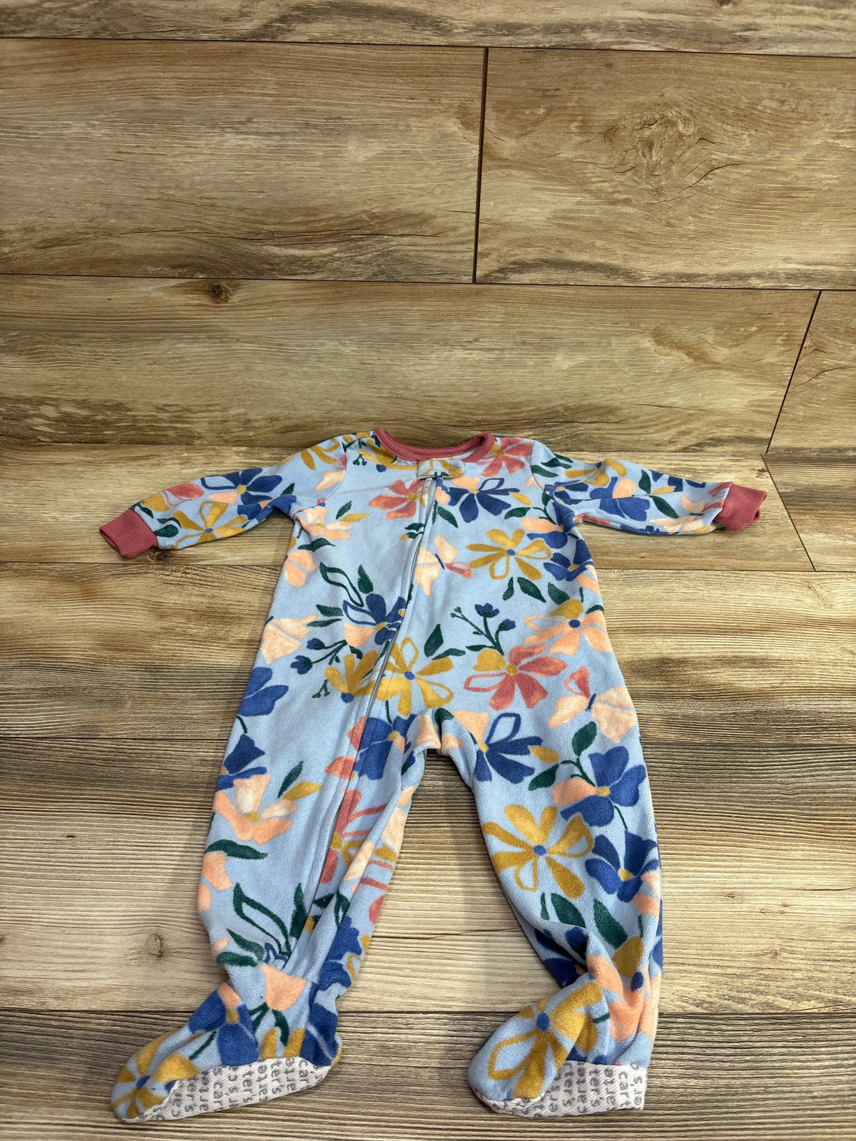 Front view of Carter’s blue floral blanket sleeper, size 12 months, showcasing footed legs and front zipper on a wood floor