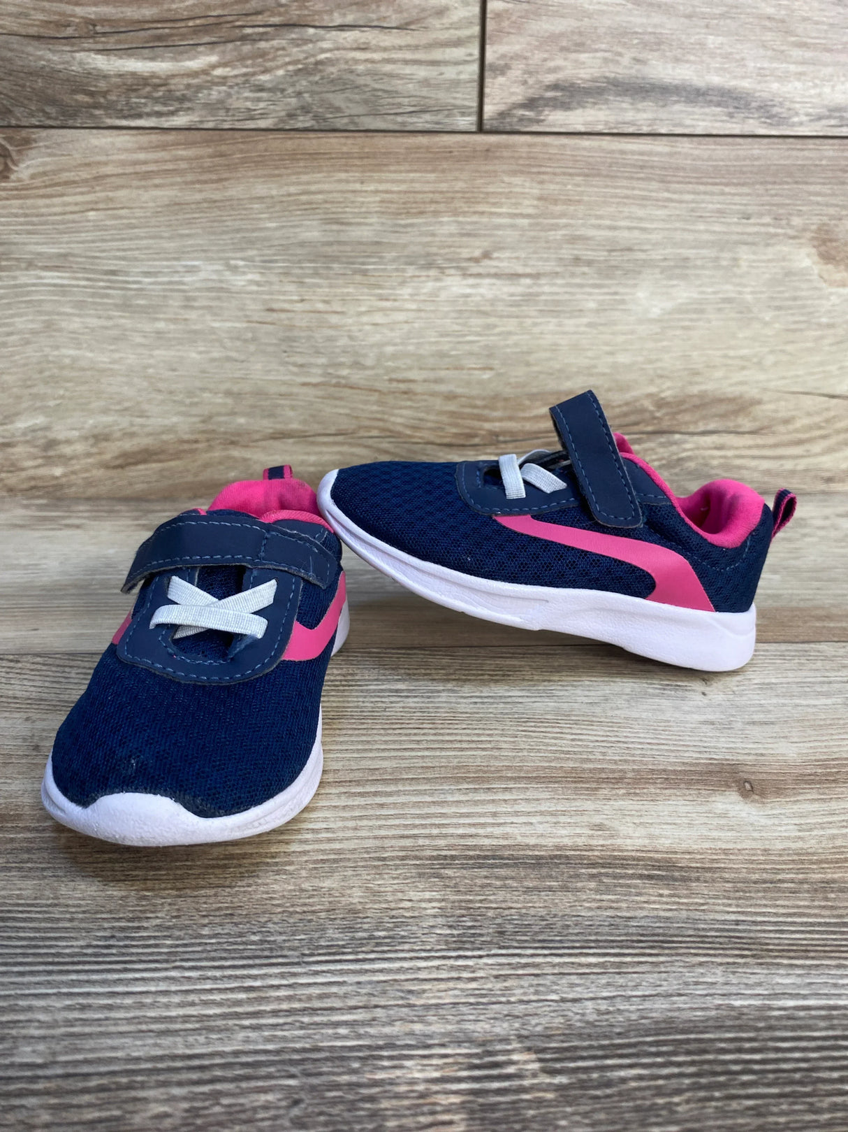 Navy blue and pink toddler athletic shoes with velcro straps on wood background